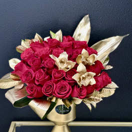 Bouquet of hot pink roses in a gold vase with metallic leaves