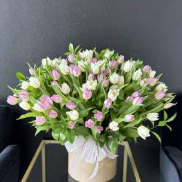 Pink and white tulips in a beige hatbox with a white ribbon