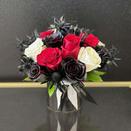 Bouquet of red, white, and black roses in a glass vase