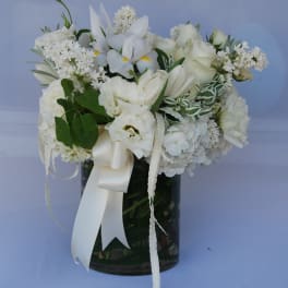 White floral arrangement in a dark glass vase with a satin ribbon