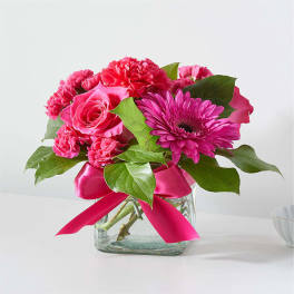 Pink mixed flower bouquet in a glass vase with a ribbon