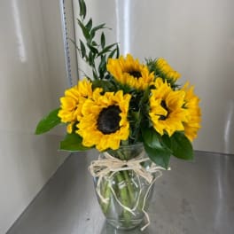 Sunflower bouquet in a clear glass vase with a raffia bow