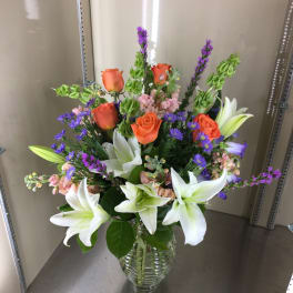 Bouquet of orange roses and white lilies in a glass vase