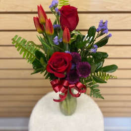 Bouquet of red roses and tulips in a glass vase with a ribbon