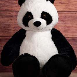 Plush panda bear sitting against a wood background