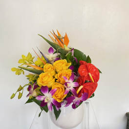 Bouquet of yellow roses, purple orchids, and red anthuriums in a clear vase