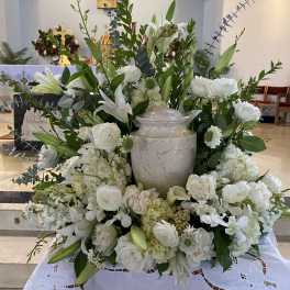 Large white floral arrangement around a marble urn in a church