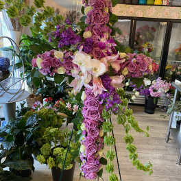 Large floral cross made of pink and purple roses with orchids