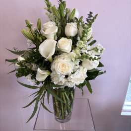 White roses, calla lilies, and lilies in a clear glass vase