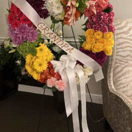 Heart-shaped floral wreath with a white ribbon and bow on a stand