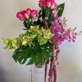 Pink roses and orchids in a clear glass vase