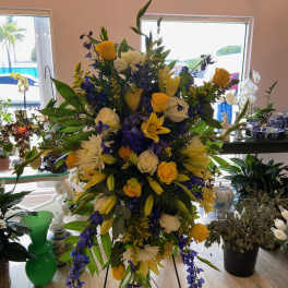 Tall floral spray with yellow, white, and blue flowers on a stand