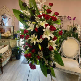 Large standing floral spray with red and black roses and white lilies