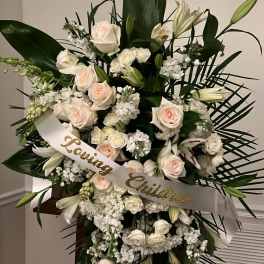 Large white floral standing spray with a "Loving Christa" ribbon