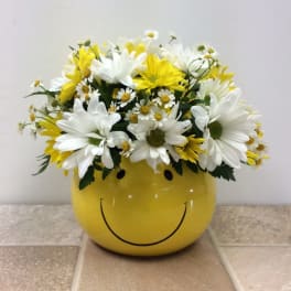 Yellow smiley-face container filled with white and yellow daisies