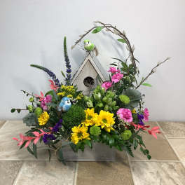 Colorful floral arrangement with a birdhouse and decorative birds