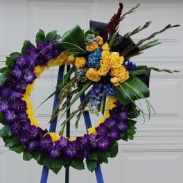 Purple and yellow floral wreath on an easel with roses and orchids