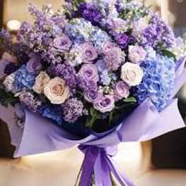 Lavender and blue bouquet of roses and hydrangeas wrapped in purple paper