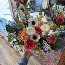 Handheld bouquet of pink, white, and lavender flowers in a glass vase