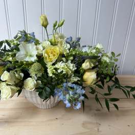 Mixed bouquet of white, yellow, and blue flowers in a white vase
