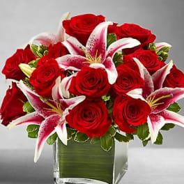 Red roses and pink lilies arranged in a square glass vase