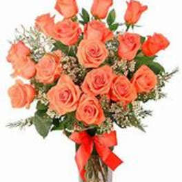 Bouquet of coral roses in a clear glass vase with a red ribbon