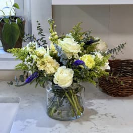 White and pale yellow flower arrangement in a glass vase