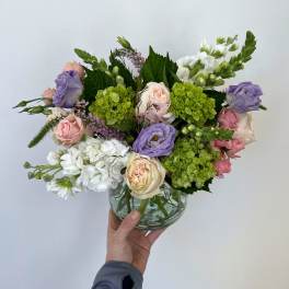 Mixed bouquet of roses, hydrangeas, and white blooms in a glass bowl vase