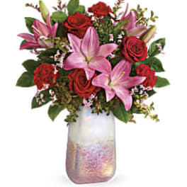 Pink lilies and red roses arranged in a frosted glass vase