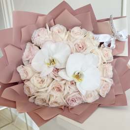 Bouquet of pale pink roses with two white orchids in pink wrapping