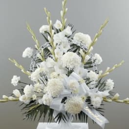 Tall white sympathy arrangement with carnations and mums in a white urn with memorial ribbon