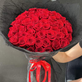 Large bouquet of red roses wrapped in black mesh with a red ribbon