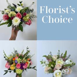 Three mixed bouquets in glass vases with a "Florist's Choice" sign