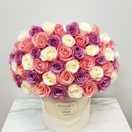 Round bouquet of pink, purple, and white roses in a cream hat box