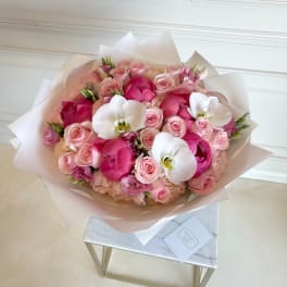 Pink rose bouquet with white orchids wrapped in pale paper