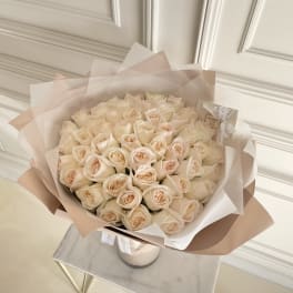 Bouquet of pale cream roses wrapped in blush paper
