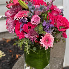 Pink and purple mixed bouquet in a green glass vase