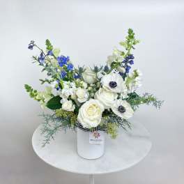 White and blue floral arrangement in a white vase