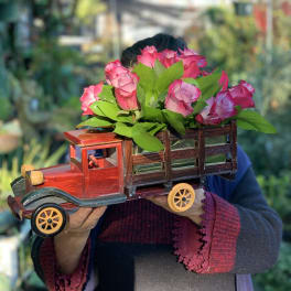 Pink roses arranged in a wooden truck-shaped container