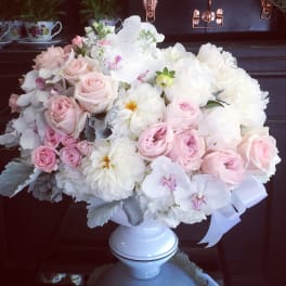Pink and white floral arrangement in a white pedestal vase