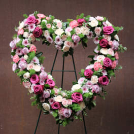Heart-shaped floral wreath on a stand with pink and white roses
