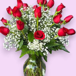Red roses arranged in a glass vase with white baby's breath