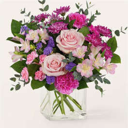 Pink roses and mixed blooms in a clear glass vase