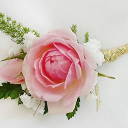 Pink rose boutonniere with white accents and green foliage