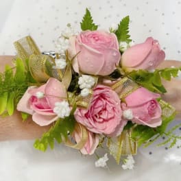 Pink rose wrist corsage with gold ribbon and white filler flowers