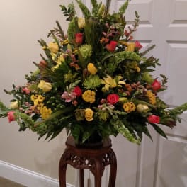 Large mixed flower arrangement on a carved wooden stand