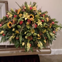Large mixed floral spray with yellow lilies, sunflowers, and roses