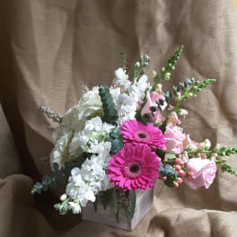 Pink gerbera daisies and white flowers in a small wooden box