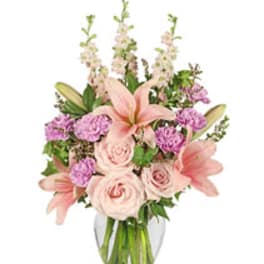 Pink lilies and roses arranged in a clear glass vase