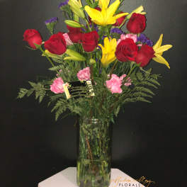 Bouquet of red roses and yellow lilies in a tall glass vase